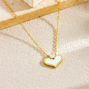Minimalist gold plated heart necklace with white shell inlay and zircon stone on stone surface