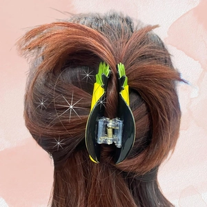 Detail of a pineapple hair claw clip in yellow and green securely holding a ponytail