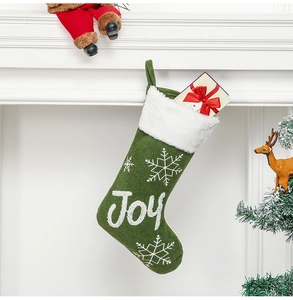 Detailed view of green Christmas stocking with white faux fur cuff and Joy embroidery