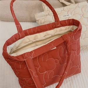 Close-up of quilted rabbit pattern on orange padded fabric bag with zipper detail