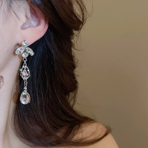 Close-up of sparkling silver tassel earrings with teardrop and rhombus crystals on model