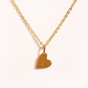 Détail du pendentif cœur doré avec gravure de la lettre C sur une chaîne de collier fine