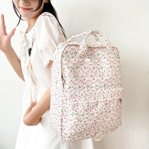 Side view of floral canvas backpack on model featuring pink flowers on off-white fabric