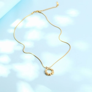 Minimalist gold necklace featuring a textured hollow circle pendant on a snake chain