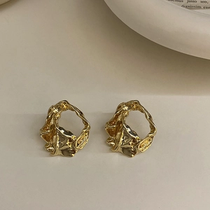 Macro detail of gold irregular hollow stud earrings with a unique textured lava finish