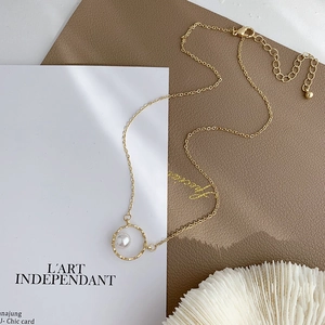 Minimalist gold necklace with geometric hollow ring and pearl accent shown at 45 degrees
