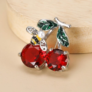 Detail of crystal cherry brooch with green enamel leaves and a small pearl bee accent