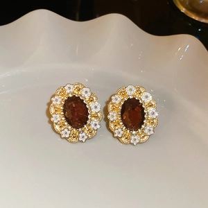 Detail of vintage oval earrings with brown gemstone and small white floral accents