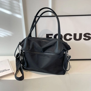 Large black nylon tote bag with leather handles and adjustable shoulder strap for travel