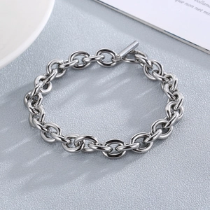 Polished silver stainless steel O-chain bracelet with stylish T-bar closure on gray texture