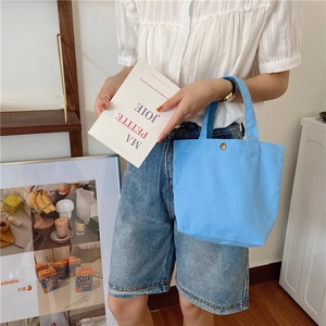 Detail of light blue canvas tote bag with metal snap closure and textured fabric