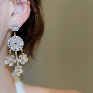 Close-up of geometric zircon flower tassel earrings with golden finish on a model