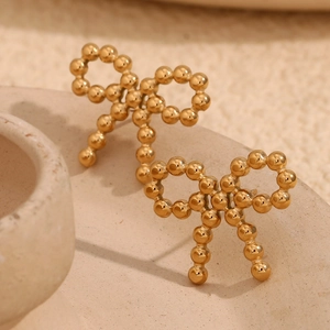 Polished 18K gold-plated beaded bow stud earrings displayed on a white ceramic tray