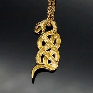 Polished gold snake pendant necklace with red eyes and detailed scales on a dark background