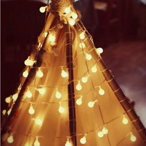 Close-up of warm white LED globe string lights decorating an outdoor camping tent