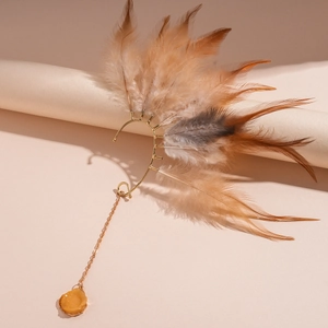 Λεπτομέρεια από χρυσό μποέμ ear cuff με φτερά και μενταγιόν από κεχριμπαρένια ρητίνη