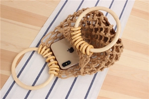 Detail view of khaki woven bag showing wooden handles and capacity for a smartphone