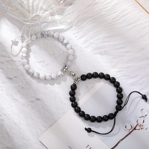 Detail of magnetic heart charms joining black and white natural stone couple bracelets