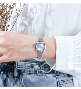 Detail of silver square watch with ice blue dial and woven mesh band on woman's wrist