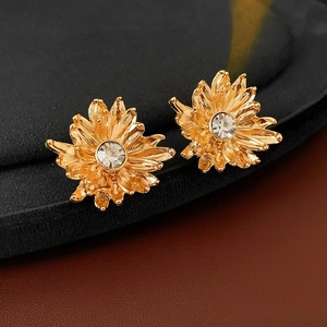 Macro shot of golden flower earrings with layered petals and a central zircon stone