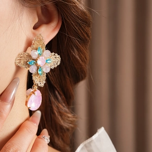 Close-up of vintage flower earring with pink and blue gems on a model's ear