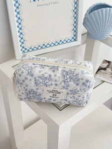 Détail de la pochette en velours côtelé matelassé avec fleurs bleues et étiquette