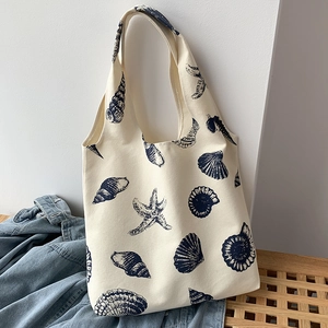 Detailed view of cream canvas tote bag with navy seashell and starfish print