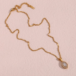 Detail of 18K gold-plated leaf eye pendant with zircon inlay and engraved jewelry tag