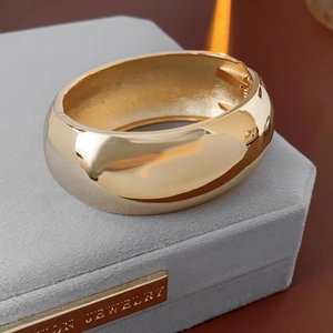 Detailed view of polished wide gold cuff bracelet on a premium jewelry display box