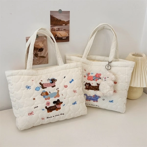 Close-up of white quilted tote bag with cute cat embroidery and soft sheep pendant