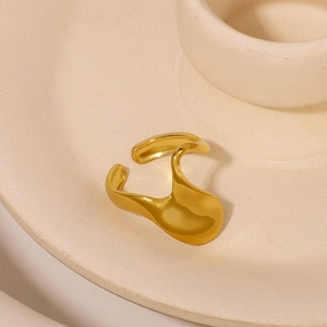 Irregular wave design stainless steel ring in gold finish on a ceramic holder