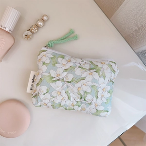 Detail of floral quilted cotton pouch with green zipper pull and simple wish woven label