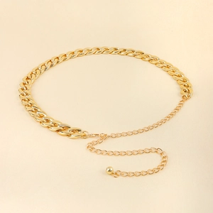 Detail view of a polished gold Cuban chain belt with lobster clasp and adjustable tail