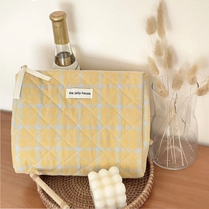 Detailed texture of quilted checkered makeup bag with woven tray and lifestyle decor
