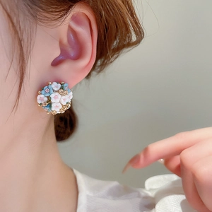 Detailed view of blue and white ceramic flower stud earrings with sparkling crystals