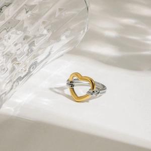 Vue macro d'une bague coeur bicolore avec coeur doré et anneau argenté sur l'eau