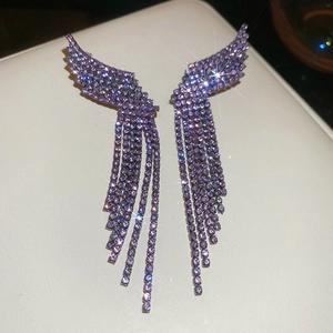 Macro detail of purple gemstone wing earrings with long sparkling tassel fringe