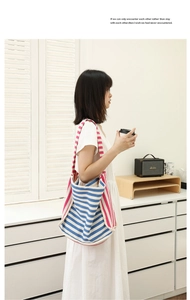 Borsa tote minimalista in tela a righe abbinata a un abito bianco in un ambiente moderno