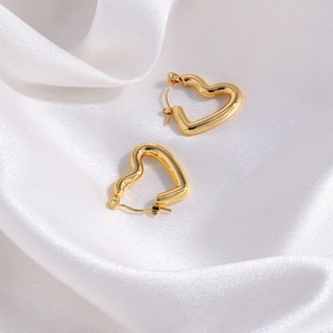 Elegant gold heart-shaped hoop earrings displayed on soft white silk fabric