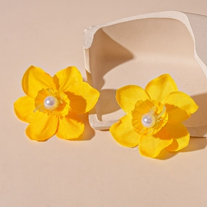Detailed macro of yellow handmade lace flower earrings with round white pearl center