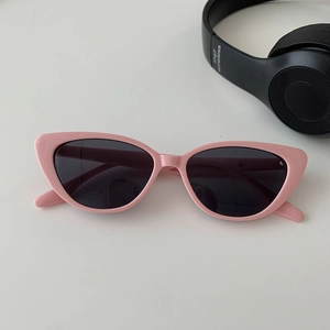Macro detail of pink cat-eye sunglasses featuring sleek frames and dark grey lenses