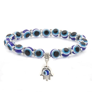 Detail view of a blue eye bead bracelet with a silver Hamsa hand charm on a white background