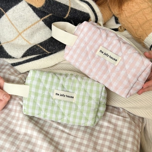 Detail of pink and green quilted gingham toiletry bags with cotton texture and strap
