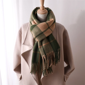 Detail of green and beige plaid scarf with soft fringe tassels on a beige coat