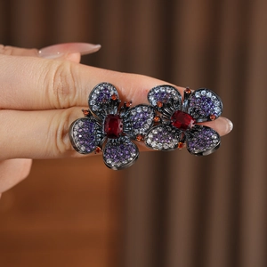 Dettaglio dell'orecchino a farfalla con zircone rosso centrale e petali viola incastonati
