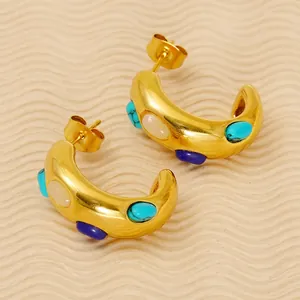 Vintage gold-tone C-shape earrings with turquoise and white stones on soft fabric