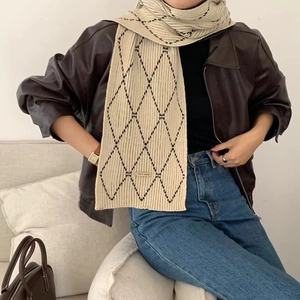Beige and black plaid knitted scarf worn with leather jacket for a cozy winter style