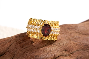 Macro shot of gold vintage hollow ring with red garnet and white diamond-like side stones