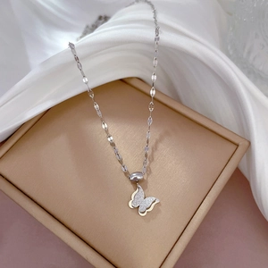 Detail of silver butterfly pendant with matte and polished wings on silk fabric