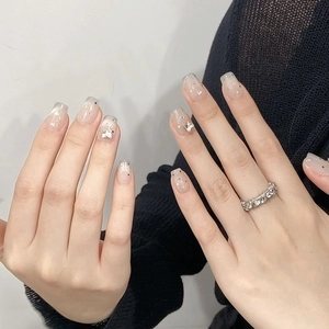 Press-on nails with butterfly crystal accents and pink glitter gradient on sheer base